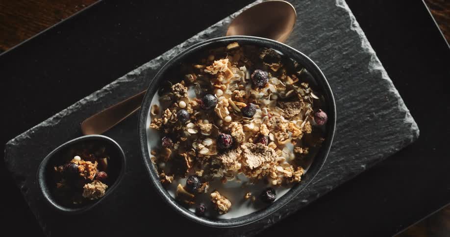 A slow moving shot of fruit and granola in a bowl of milk