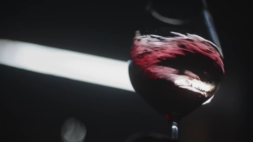 Someone is swirling red wine around in a wine glass