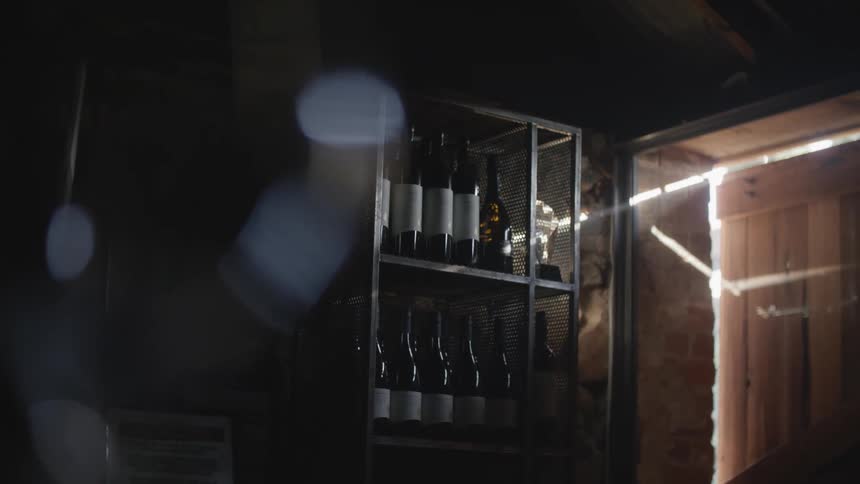 Bottles of wine sit on a shelving rack in a dark cellar