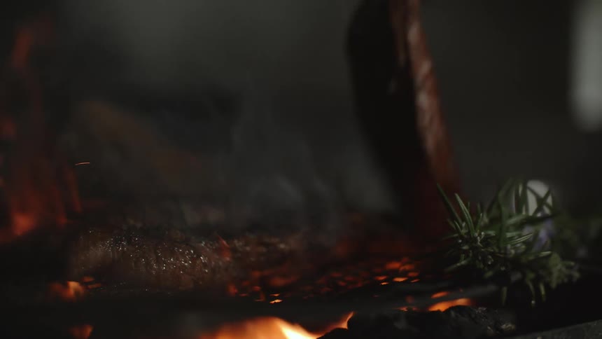 A person flips a steak on the grill