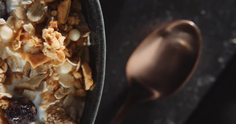 A bowl of granola sitting next to a spoon on a table