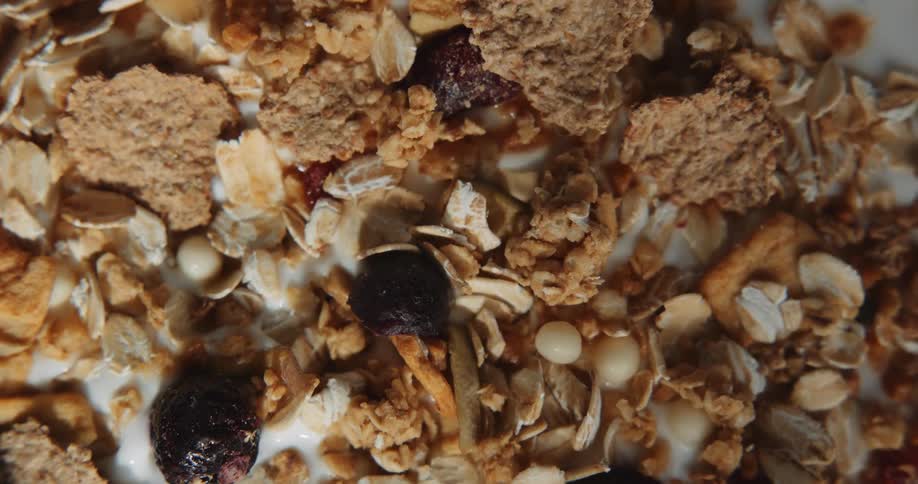 An up close shot of granola and fruit against something white