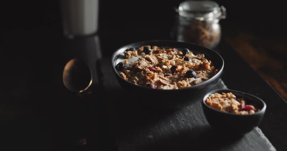 A bowl of cereal with berries on a table indoors during the day