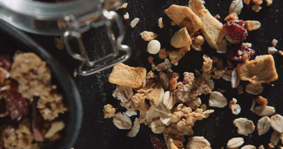 An up close view of granola and crumbs on a black surface