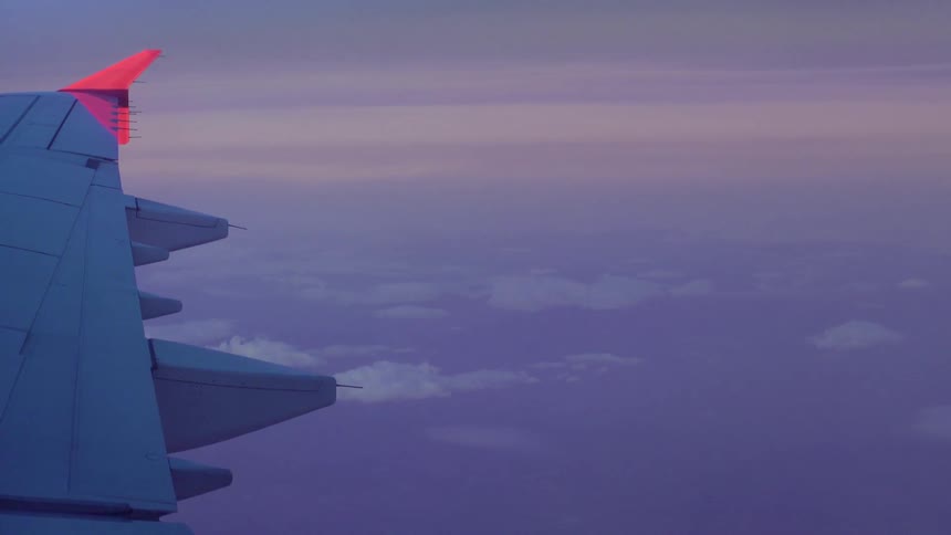 The wing of an airplane flying in the sky above clouds