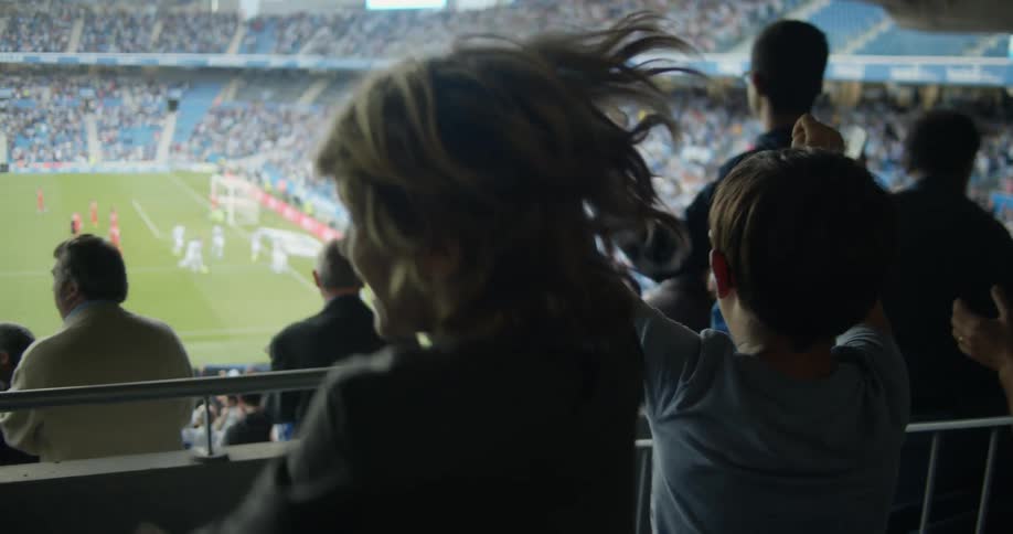 Two little boys raising their arms jumping and cheering in a stadium