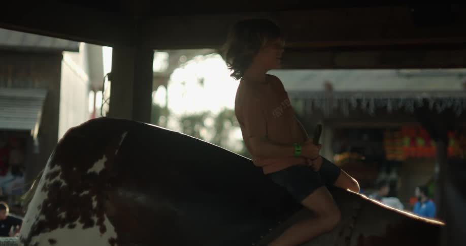 Happy boy riding a mechanical bull and having fun