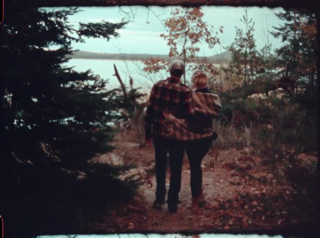 Man and woman embracing while walking towards a lake