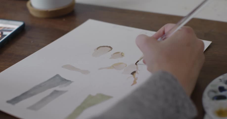 A female is sitting at a desk and painting a picture
