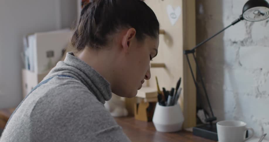 A female artist sketching on paper while sitting at a desk