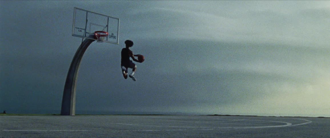 A male is outdoors playing basketball by himself