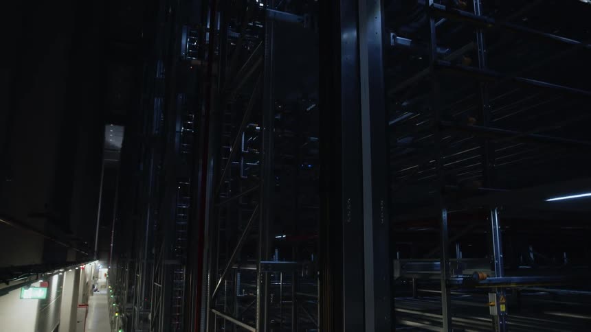 An FPV drone shot gliding upward to show a large metal structure in a distribution warehouse building