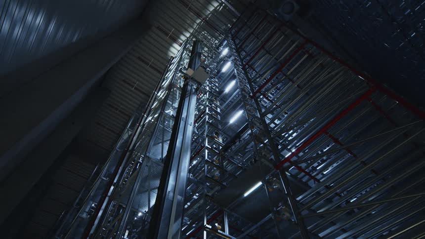 A tall distribution warehouse with robotic lifts and mechanisms on the shelving structure