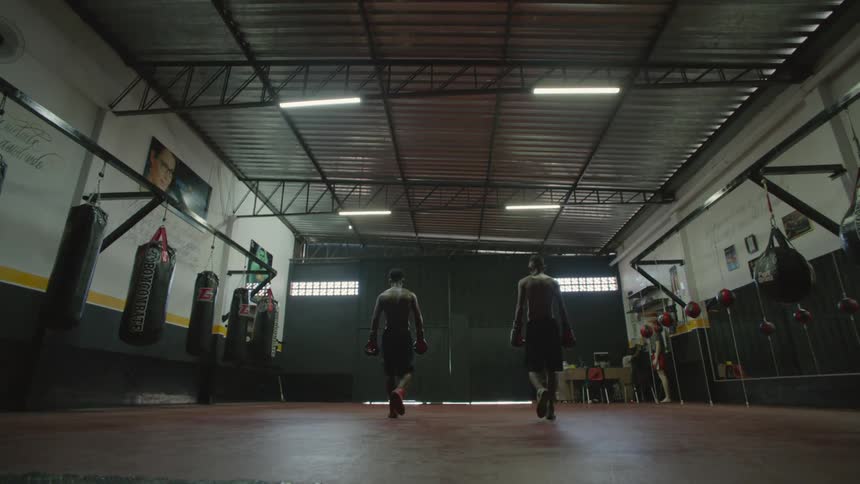 Two boxers walking out of a gym together as lights turn on