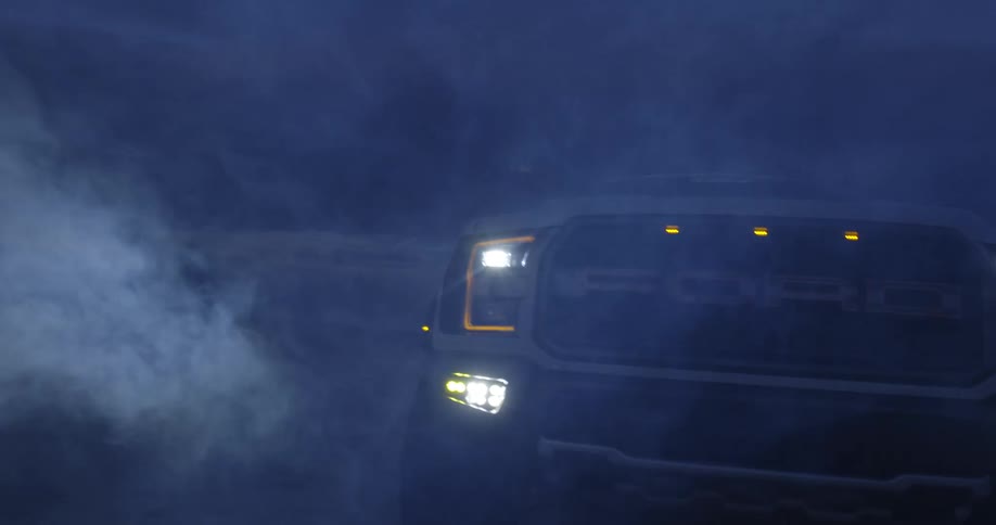 Headlights on truck parked in desert come on to illuminate fog