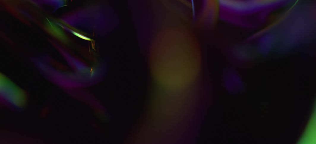 Translucent shapes are reflecting neon fluorescent light as they bend and move in the darkness