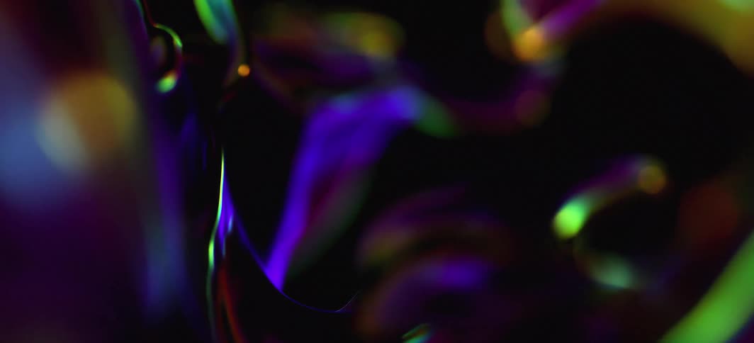 Computer generated abstract forms animating and refracting light in dark environment with a black background