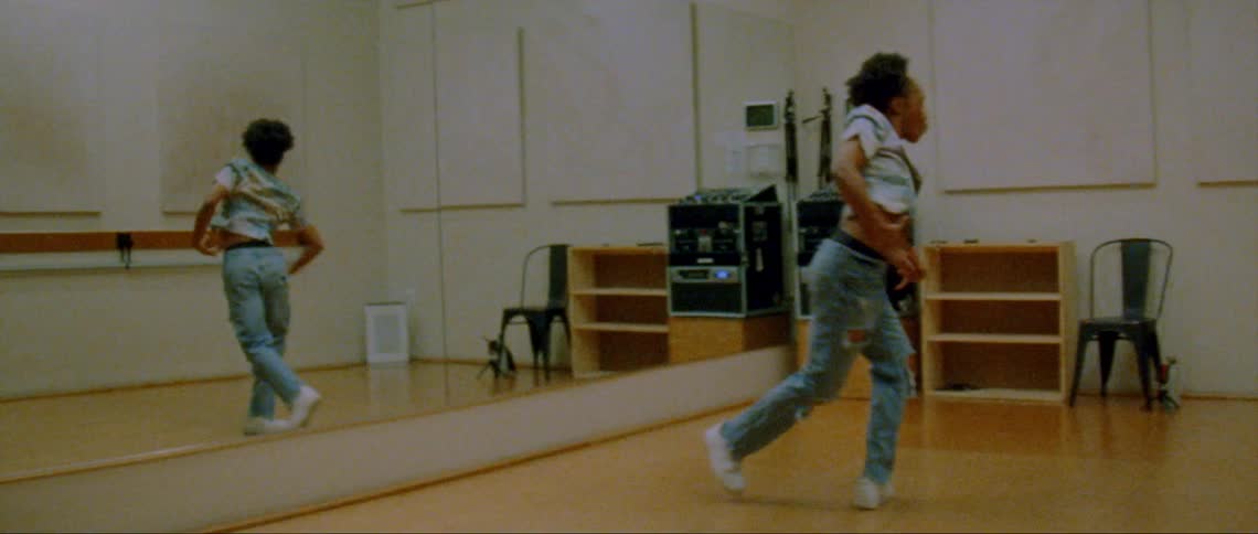 A young black woman is dancing inside of a studio