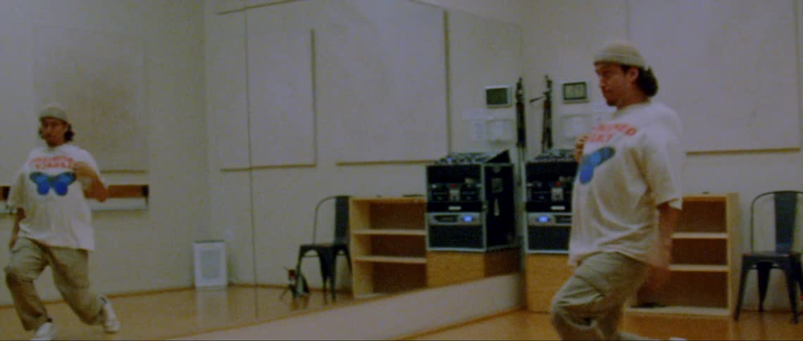 A male is dancing in front of a mirror in a room