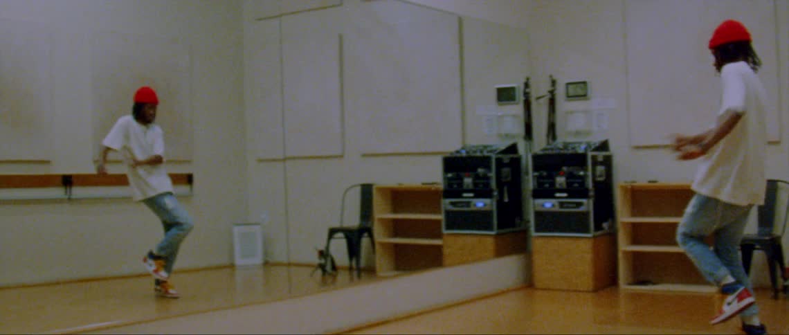 A man is dancing in front of a mirror in a room