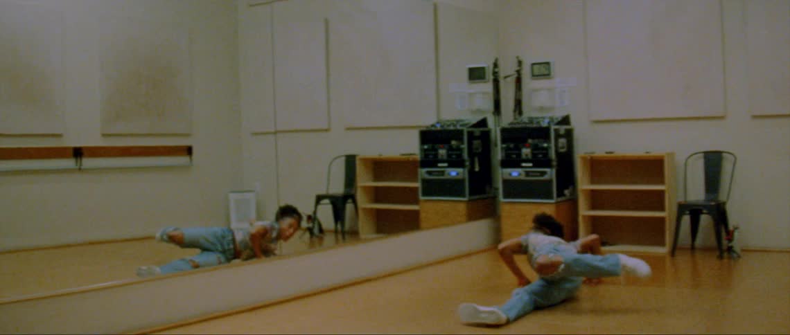 A woman is dancing in a room by herself in front of a mirror