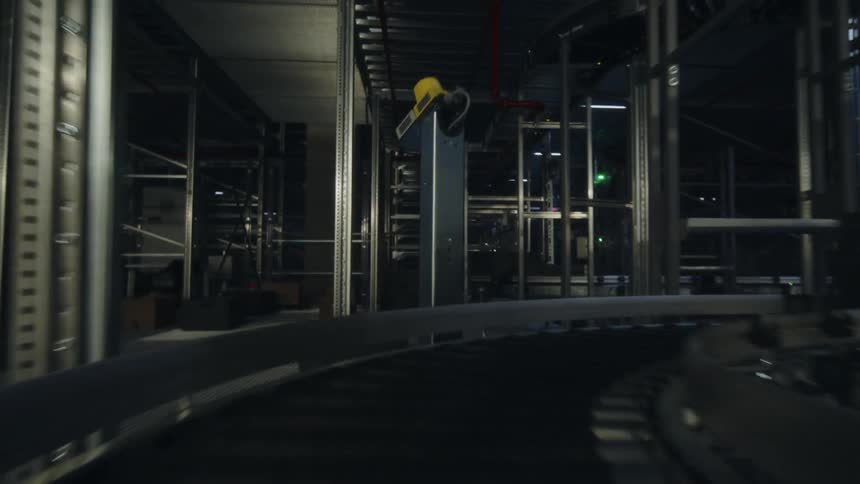 A first-person POV shot of a box moving through an automated distribution warehouse or fulfillment center