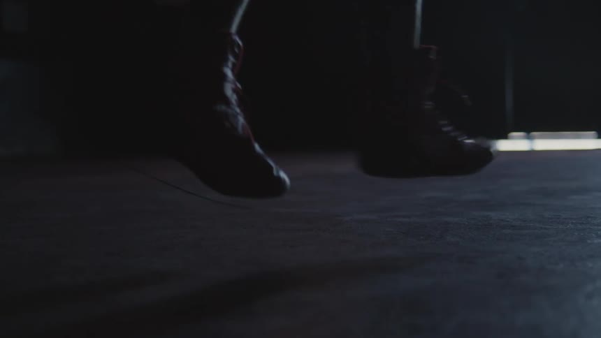 A persons feet dancing on a dark floor in a dark space