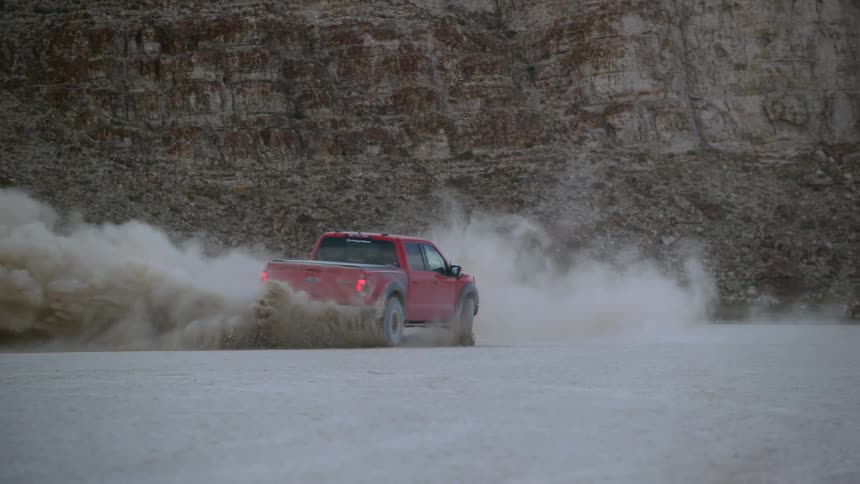 A vehicle is driving on a dirt road in a rural area
