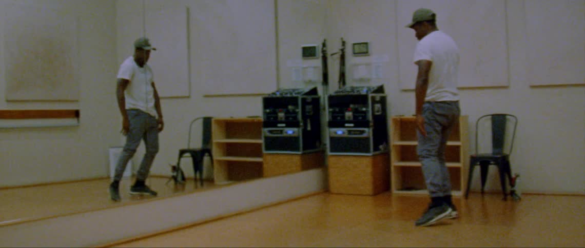 Young man energetically dancing in front of a mirror on a studio