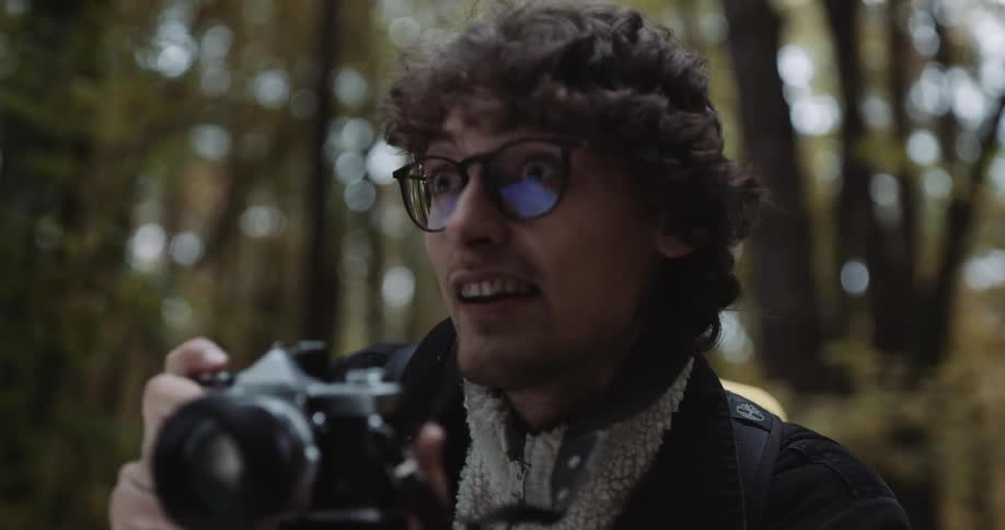 A male is taking photos with a camera in a wooded area