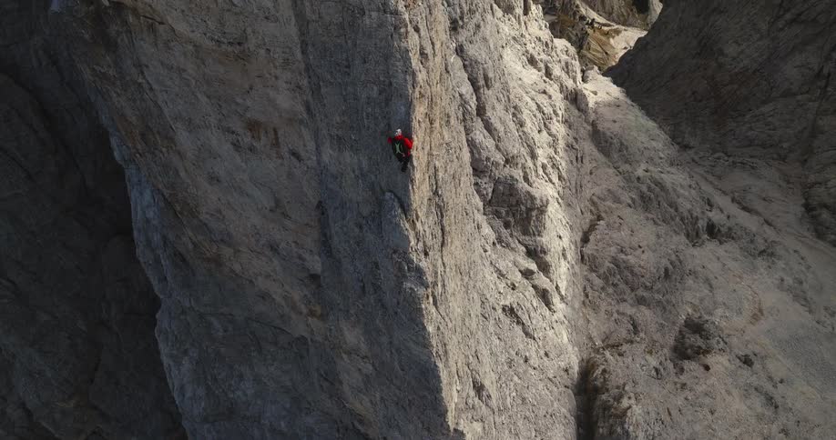 A person is rock climbing up a mountain during the day time