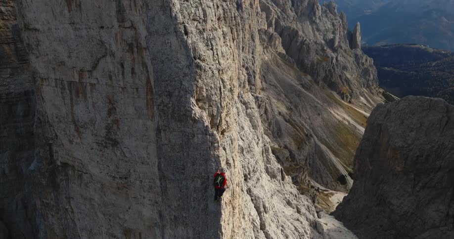 A person is climbing up a mountain during the daytime