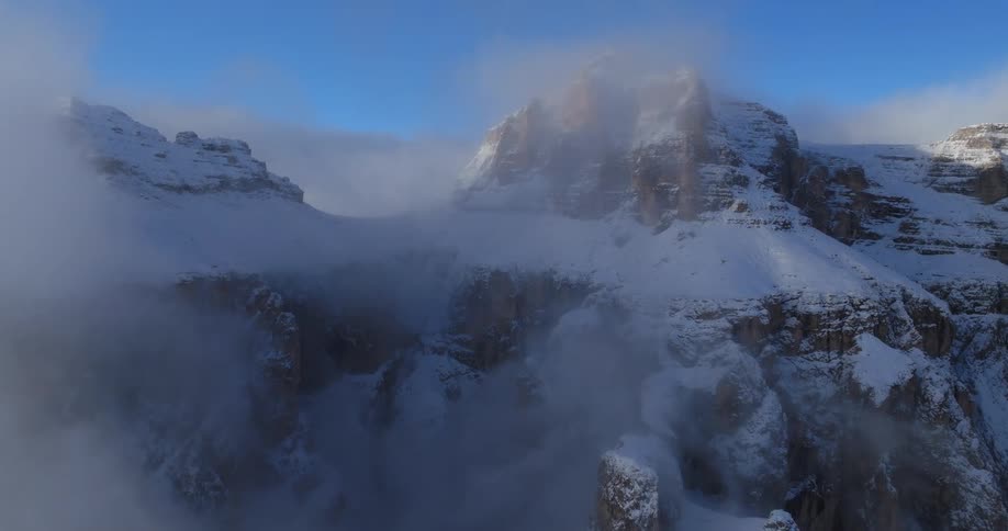 A snowy mountain ridge shrouded in mist on a clear day