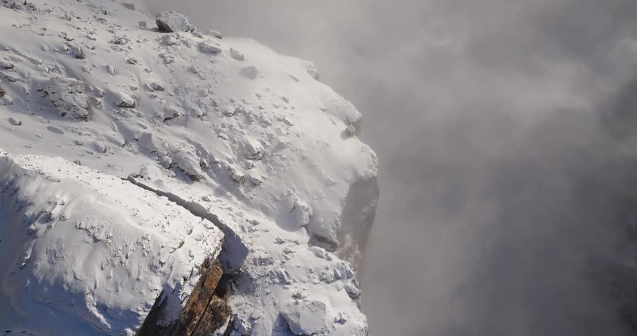 An aerial view of a snowy mountainside in the wilderness on a foggy day