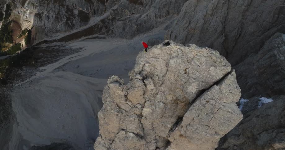 An aerial view of a rock climber standing on top of a rocky ridge
