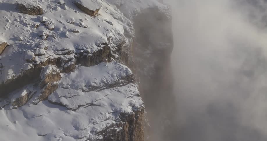 A snowy cliffside in the wilderness on a foggy day