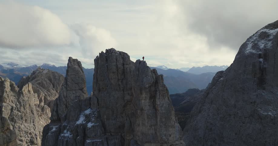 An aerial view of mountains with a man standing on the middle one