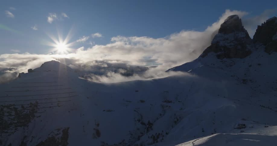 Sun shines brightly on snow covered mountainsone with face covered in parallel terraces