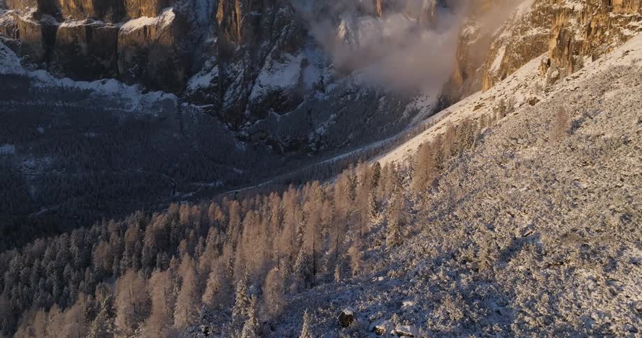 An aerial view of a snow covered mountain and cliffs at dawn