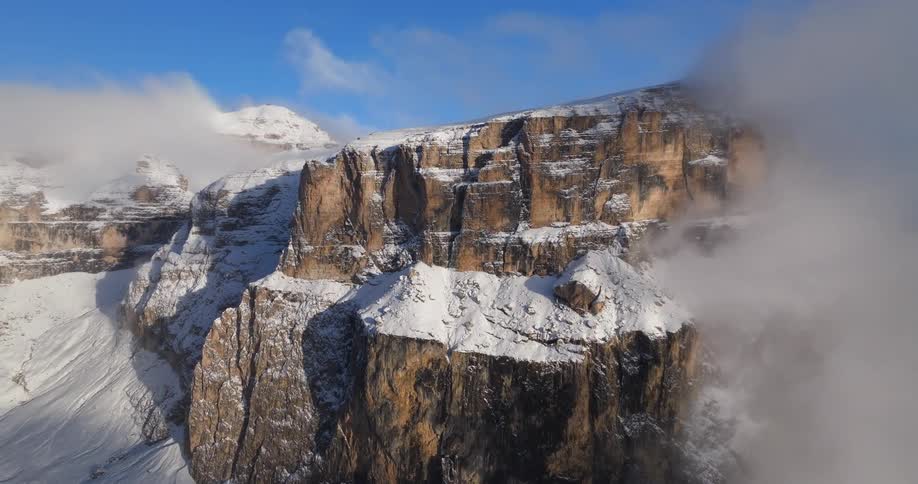 An aerial view of a snowy cliffside in the wilderness on a winter day