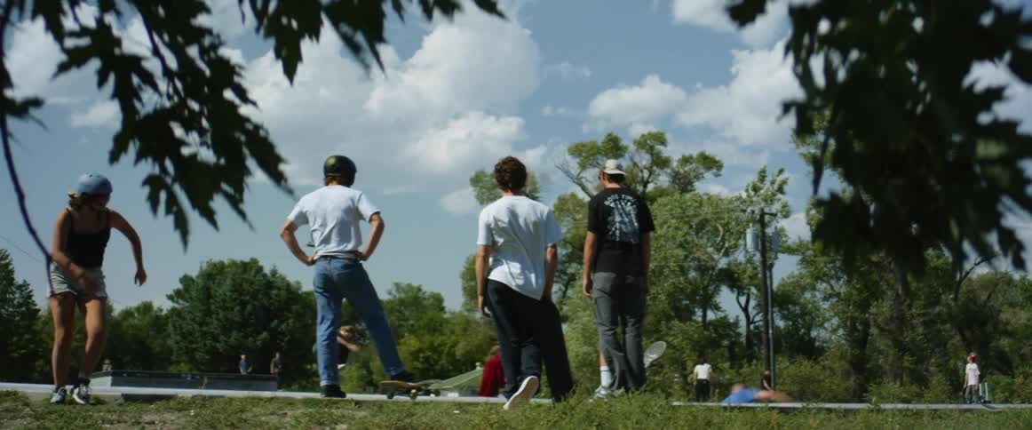A group of teens stand watch other people at a skate park