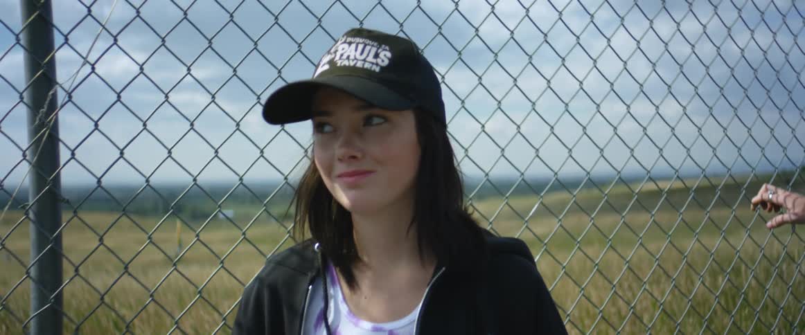 A girl is standing by a fence outdoors in spring