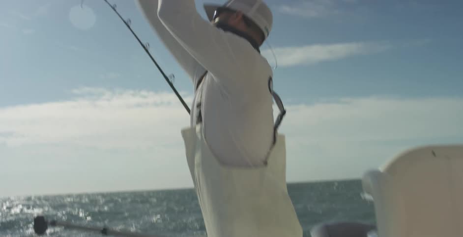 A young man is on a boat fishing on a lake in the day time