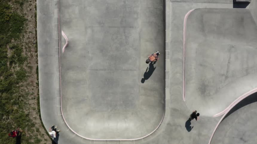 A skateboarder skates within a pool in a skate park during the day