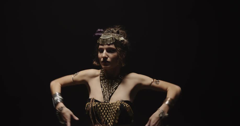 A woman wearing an arabian genie dress is dancing with an all black background