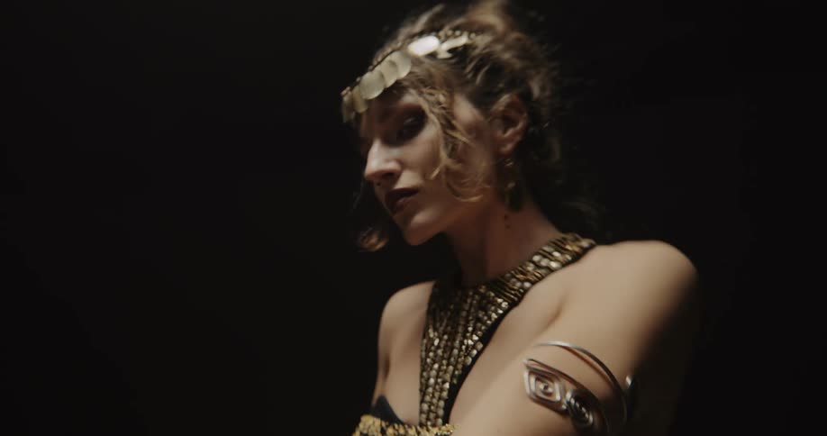 A woman wearing eccentric jewelry dancing and moving her arms and hands around