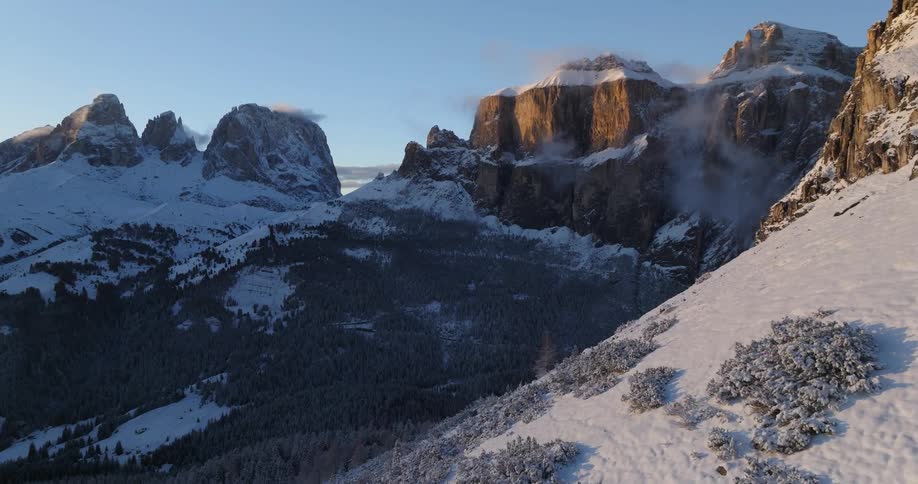 An aerial view of a snowy mountainside surrounded by other mountains