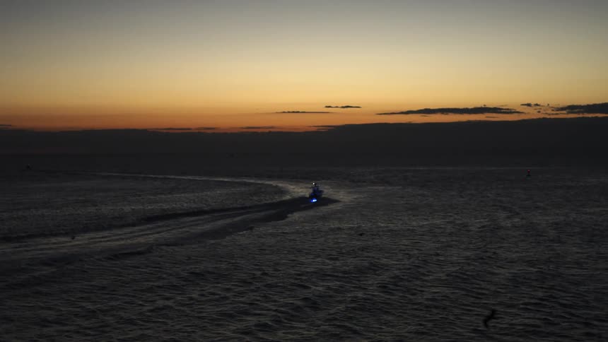 Aerial view of a boat sailing on the calm ocean waters at evening