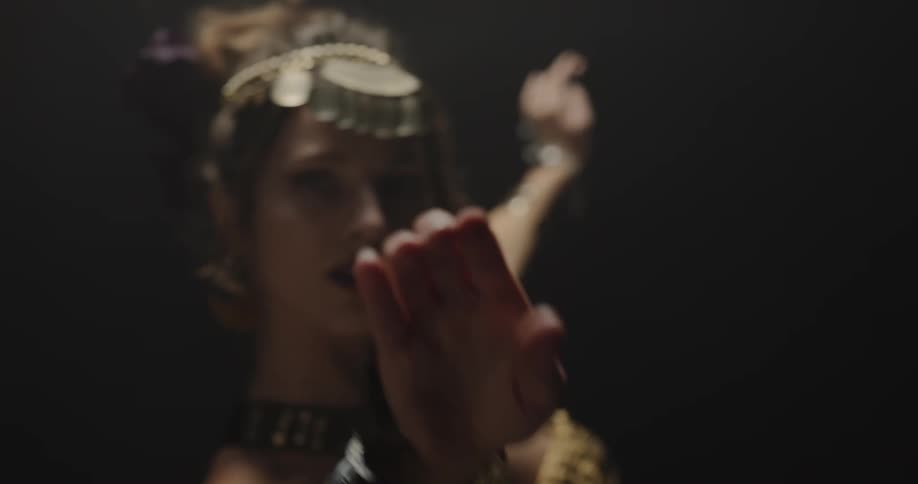 Belly dancer in bedlah headbands with golden coins golden necklace and bracelets performs dance and moves of the hips and torso on stage