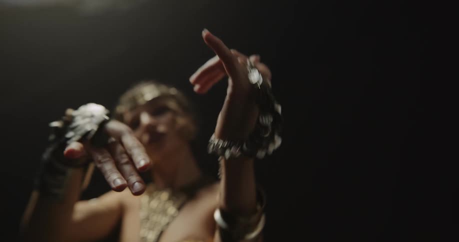 A woman is dancing by herself and wearing a lot of jewelry